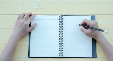 Kadın sarı bir arka plan ile bir kil kitap kitap yazdı. Üstten görünüm.