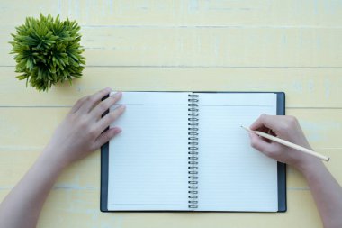 Kadın sarı bir arka plan ile bir kil kitap kitap yazdı. Üstten görünüm.