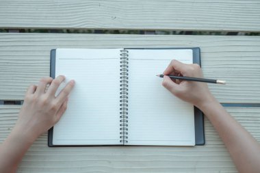 Kadın sarı bir arka plan ile bir kil kitap kitap yazdı. Üstten görünüm.