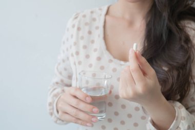 Bir tıp ve bir bardak su onun elinde tutan bir kadın. Tıbbi ve sağlık kavramları