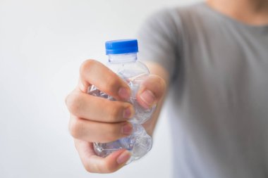 beyaz zemin üzerinde bir geri dönüşümlü plastik şişe tutan el.