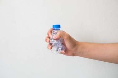 beyaz zemin üzerinde bir geri dönüşümlü plastik şişe tutan el.