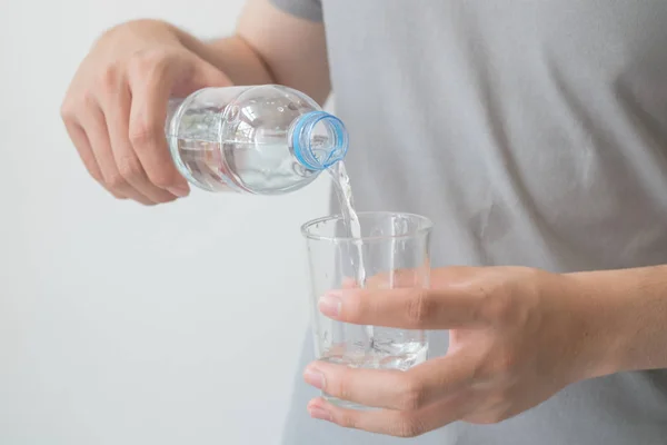 stock image man hand holding a bottle of water Pouring water into a glass.