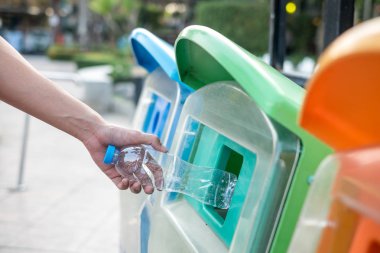 Adam el holding ve plastik şişe atık çöp çöp kutusuna koyarak.