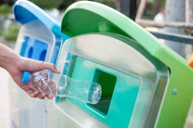 Adam el holding ve plastik şişe atık çöp çöp kutusuna koyarak.