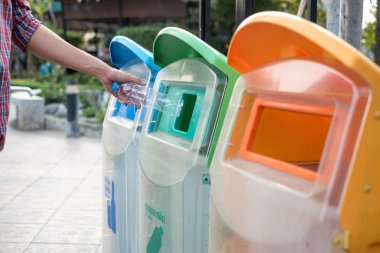 Adam el holding ve plastik şişe atık çöp çöp kutusuna koyarak.