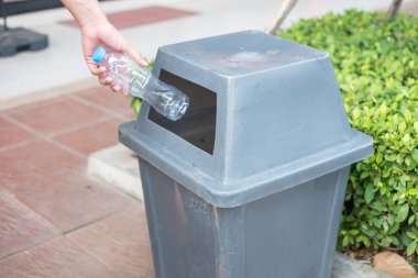 Adam el holding ve plastik şişe atık çöp çöp kutusuna koyarak.