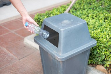 Adam el holding ve plastik şişe atık çöp çöp kutusuna koyarak.