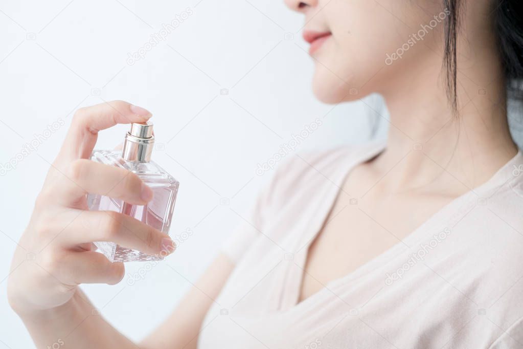woman is spraying perfume at the neck.