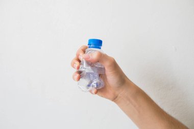 beyaz zemin üzerinde bir geri dönüşümlü plastik şişe tutan el. 