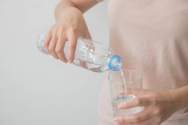 Bir şişe su tutan kadının eli bir Glas içine su dökme