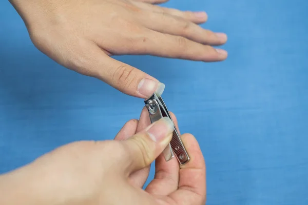Un hombre se corta las uñas usando un par de recortes de uñas metálicos. — Foto de Stock