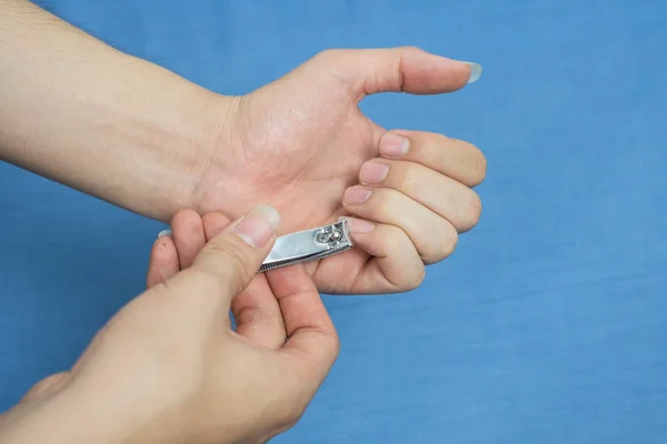 Un hombre se corta las uñas usando un par de recortes de uñas metálicos. — Foto de Stock