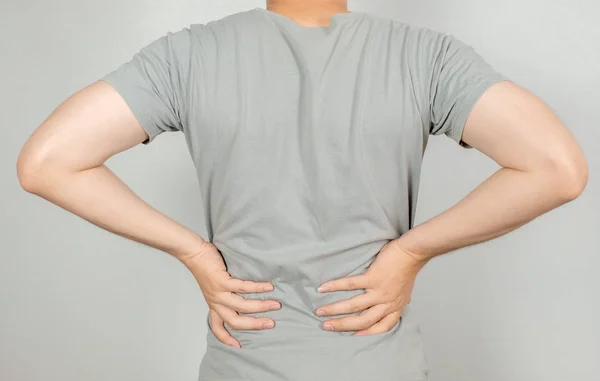 Ein Mann hielt ihre Hand mit Rückenschmerzen hinter sich. Gesundheitskonzept — Stockfoto