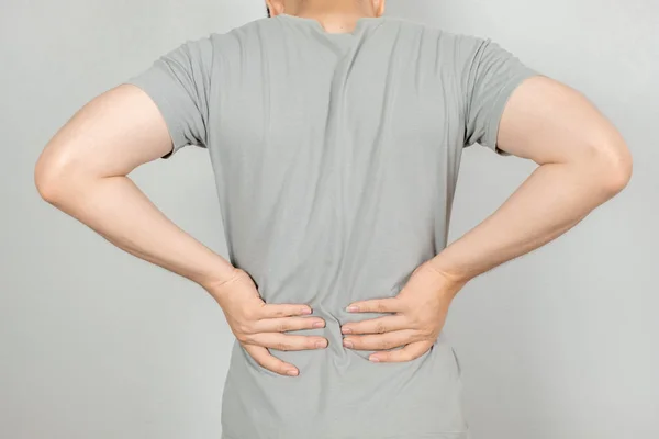 Ein Mann hielt ihre Hand mit Rückenschmerzen hinter sich. Gesundheitskonzept — Stockfoto