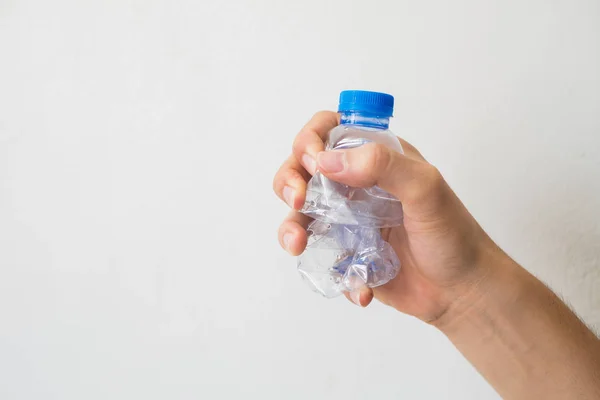 Hand hält eine recycelbare Plastikflasche auf weißem Hintergrund. lizenzfreie Stockbilder