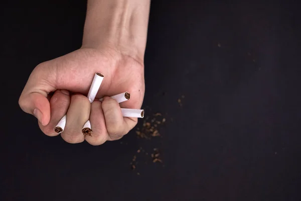 Raucherentwöhnung, Zigarettenvernichtung in der Hand isoliert auf schwarzem Rücken — Stockfoto