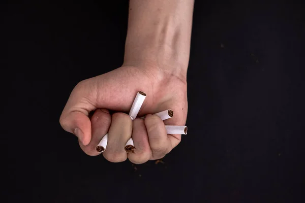 Raucherentwöhnung, Zigarettenvernichtung in der Hand isoliert auf schwarzem Rücken — Stockfoto