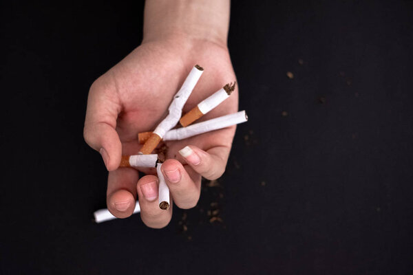 Бросить курить, держать сигарету в руках уничтожить изолированы на черном фоне
