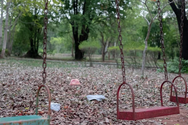 Kinderschaukeln hängen leer im Leerlauf auf einem Spielplatz an einer langweiligen Stelle, Stockfoto