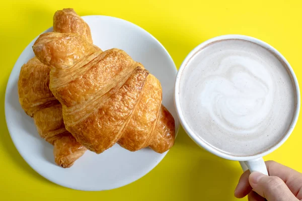 Croissant e cacau quente ou chocolate quente em um fundo amarelo , — Fotografia de Stock