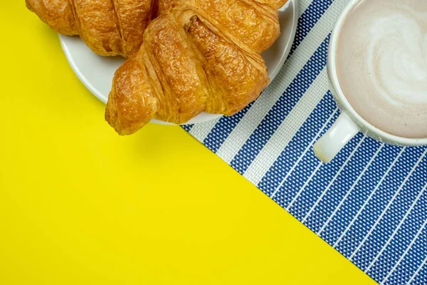 Croissant e cacau quente ou chocolate quente em um fundo amarelo , — Fotografia de Stock