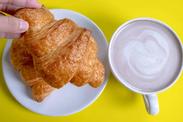 Croissant e cacau quente ou chocolate quente em um fundo amarelo , — Fotografia de Stock