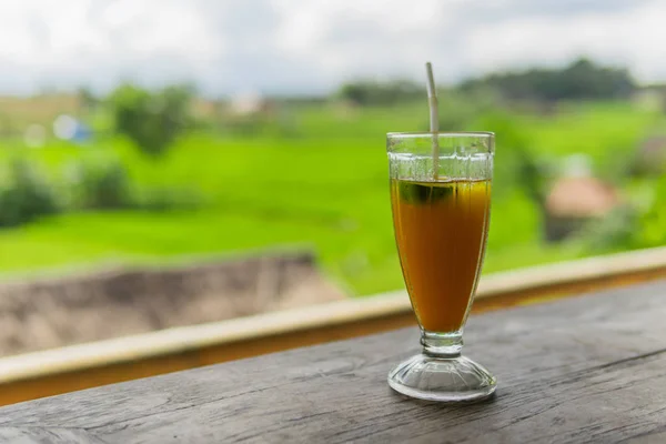 Mango papaya banana iced drink with rice fields in the background.