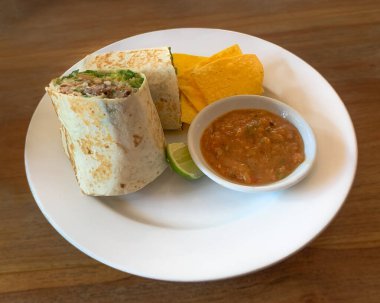 Mısır cipsi, tortilla ve salsa soslu biftek burrito..