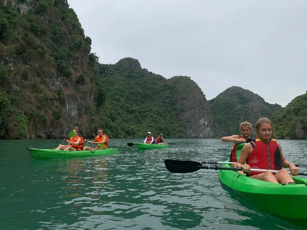 Cat Ba, Vietnam - 19 Kasım 2019: Ha Long Körfezi yakınlarındaki bir grup turist kanosu, karst dağı arasındaki bulutlu bir günde, popüler eğlence aktivitesi.