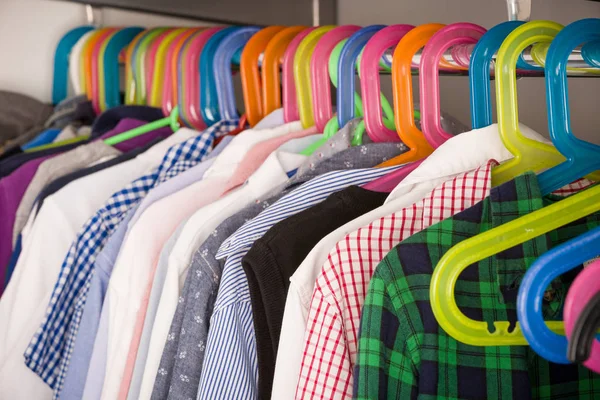 Children clothes on hangers in a room. wardrobe with boy's clothes on hangers. Shopping and consumerism concept. Dressing closet with clothes arranged on hangers.Colorful wardrobe for kids.