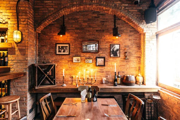 Rahat bir atmosfer yaratan sıcak ışıkta tuğla ve fotoğraf çerçeveleri ile dekore edilmiş İtalyan restoranının yemek masası.