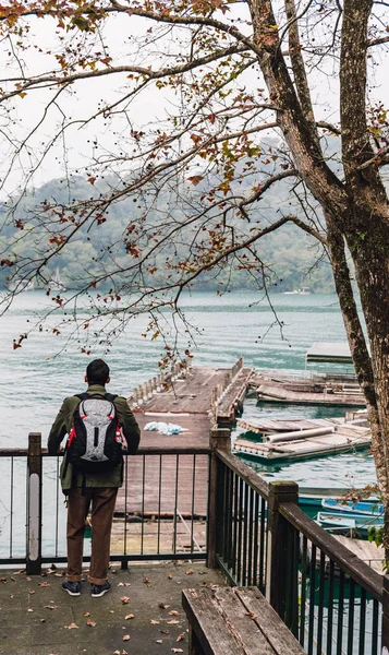 Back view of man standing and looking on Sun Moon Lake in Yuchi Township, Nantou County, Taiwan