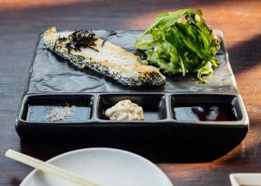 Japon Levrek Fileto Biftek salata ile servis, mayonez ve shoyu sos taş plaka üzerinde.
