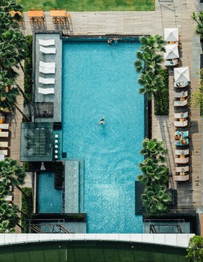 Yüzen bar ile yüzme havuzu üst görünümü, insanlar plaj sandalyeleri ve yaz aylarında yüzen bir adam yatıyordu.