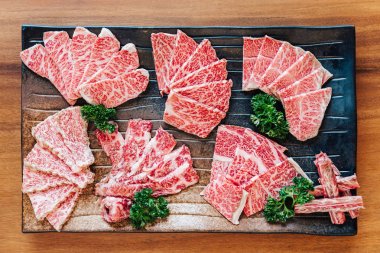 Top view of Premium Rare Slices many parts of Wagyu A5 beef with high-marbled texture on stone plate served for Yakiniku (Grilled Meat). clipart