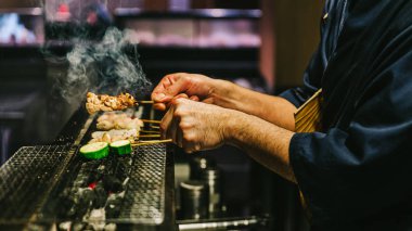 Japon Yakitori Chef Eller ızgara tavuk zencefil, sarımsak ve soya sosu ve salatalık duman bir sürü ile marine.