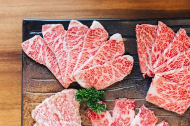 Close-up top view of Premium Rare Slices many parts of Wagyu A5 beef with high-marbled texture on stone plate served for Yakiniku (Grilled Meat). clipart