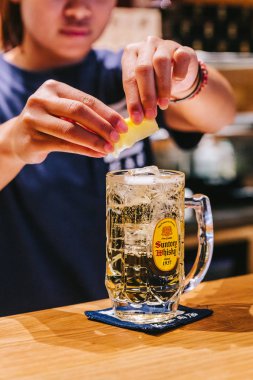 Kadın barmen Japon Viski Highball üzerinde limon bir dilim sıkma. 