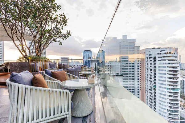 Outdoor rooftop bar with outdoor sofa sets in the evening. This space can take a view of modern buildings in Bangkok.