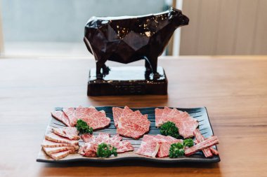 Premium Nadir Dilimler Taş plaka üzerinde yüksek mermer doku ile Wagyu A5 sığır eti birçok yerinde Yakiniku (Izgara Et) için servis. Arka planda Japon parçaları heykel ile.