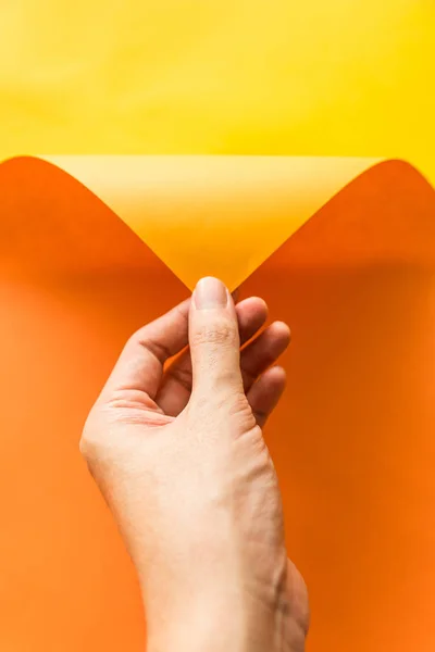 Hand Zieht Orangefarbenes Papier Aus Gelbem Papierhintergrund Abstrakte Farbe Papier — Stockfoto