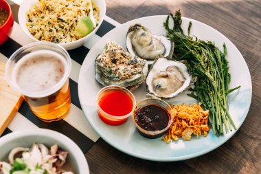 Kızarmış arpacık soğanı, acı biber ezmesi, Acacia Pennata ve Tayland usulü deniz ürünleri sosuyla servis edilen kabuklu taze istiridye. Tayland usulü yemek..