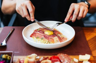 El elinde bıçak ve çatal parma jambon ve karabiber ile sarısı ile Fettuccine Carbonara yemek için. Beyaz tabakta servis edilir.