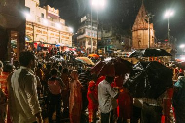 Varanasi Ganga Aarti 'deki kutsal Dasaswamedh Ghat' ta, Varanasi, Hindistan 'daki Kashi Vishwanath Tapınağı yakınlarındaki yağmurda kutsanmayı bekleyen kalabalık bir grup insan..