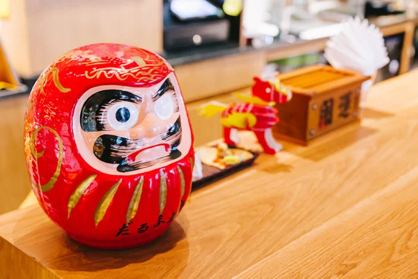 Daruma doll (Japanese traditional doll) on wooden counter with copy space.