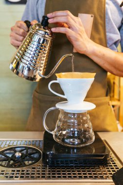 Barista damlama denilen alternatif yöntem ile dökme kahve yapma. Kahve öğütücü, kahve standı ve dökme-üzerine ahşap bir masa üzerinde.