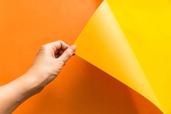 Hand Zieht Orangefarbenes Papier Aus Gelbem Papierhintergrund Abstrakte Farbe Papier — Stockfoto