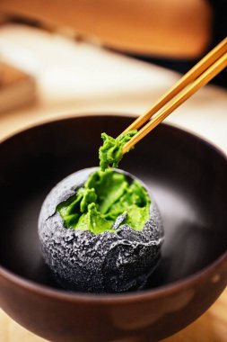 Bir kepçe ev yapımı yeşil çay ile kaplanmış kömür Japon çay evi tatlı kafesinde yemek çubuklarıyla çimdiklenmiş. Asya usulü lezzetli egzotik füzyon tatlısı..