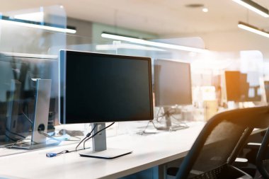 Ofiste monitörle birlikte masada akrilik pleksiglas ayırıcı ayarlanıyor. Covid-19 salgını sırasında ofisteki sosyal mesafeler için yeni normal kavram. Önlem ve güvenli..